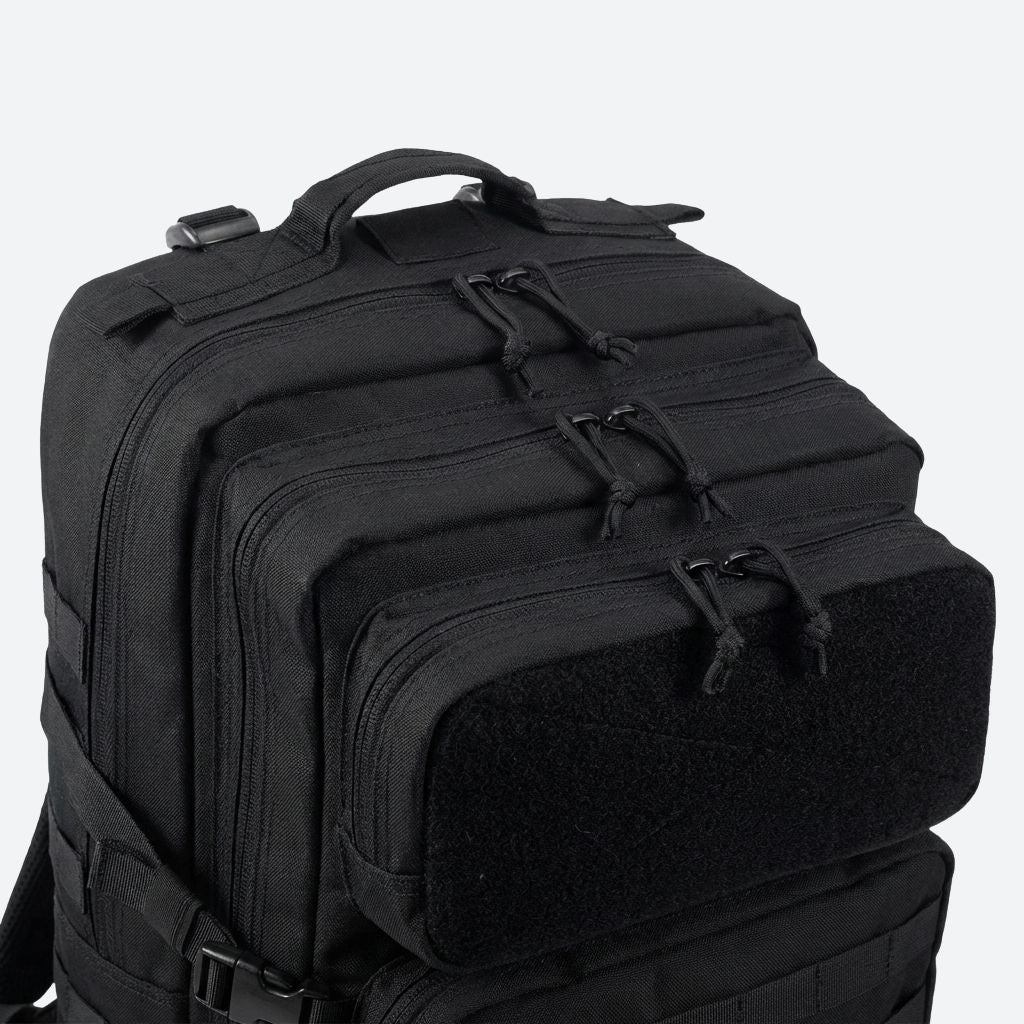 Détail du haut du sac tactique noir, poignée robuste de transport et poche velcro supérieure libre sans patch