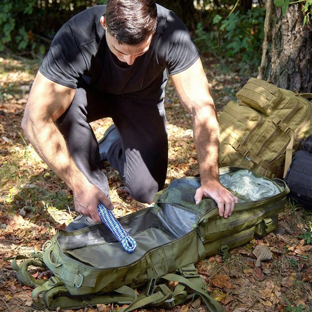 Homme en tenue tactique ouvrant à 180° un grand sac à dos militaire vert sur feuilles mortes en forêt Image
