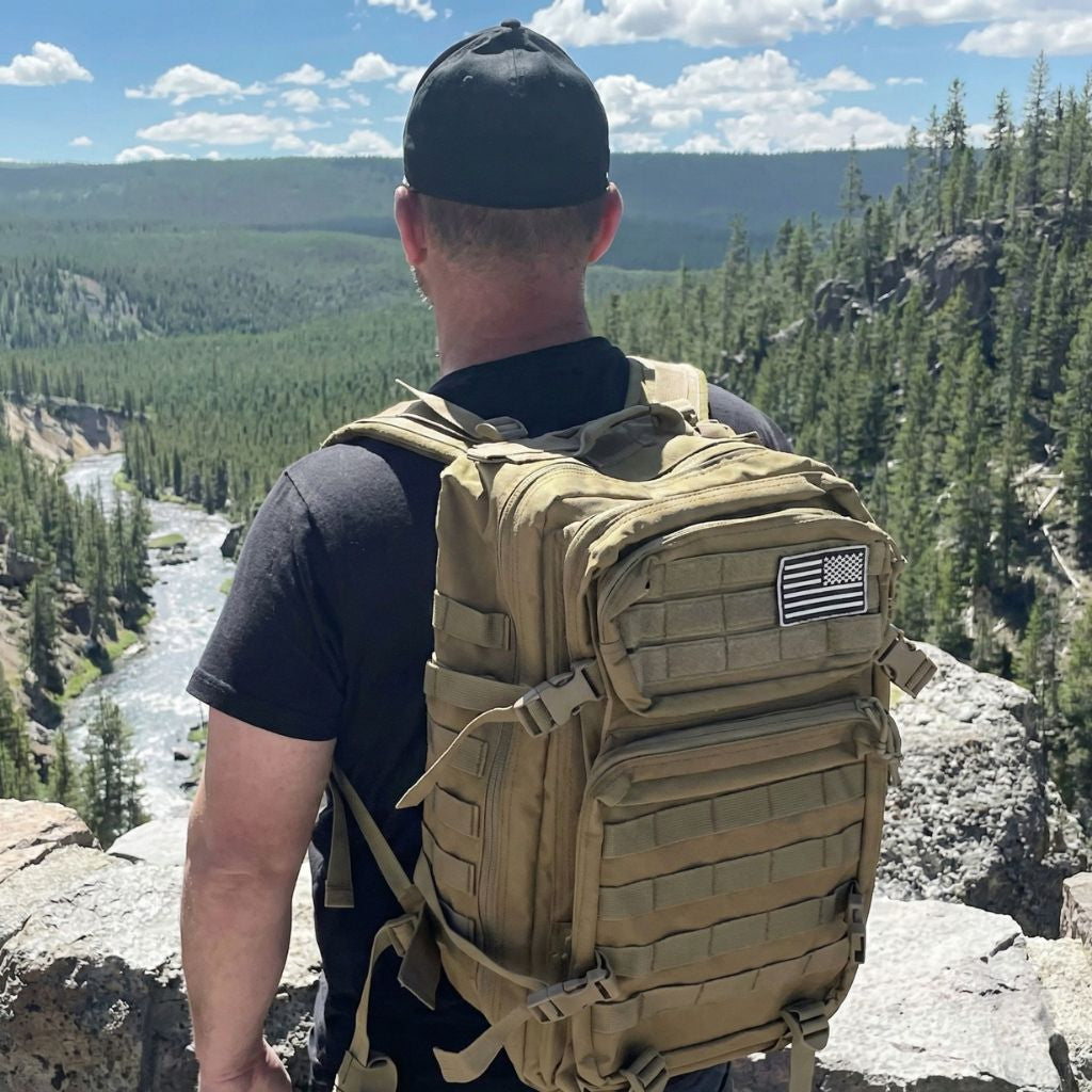 Lifestyle : homme portant le sac à dos militaire 45L tan coyote vue de dos en montagne sur rivière sauvage