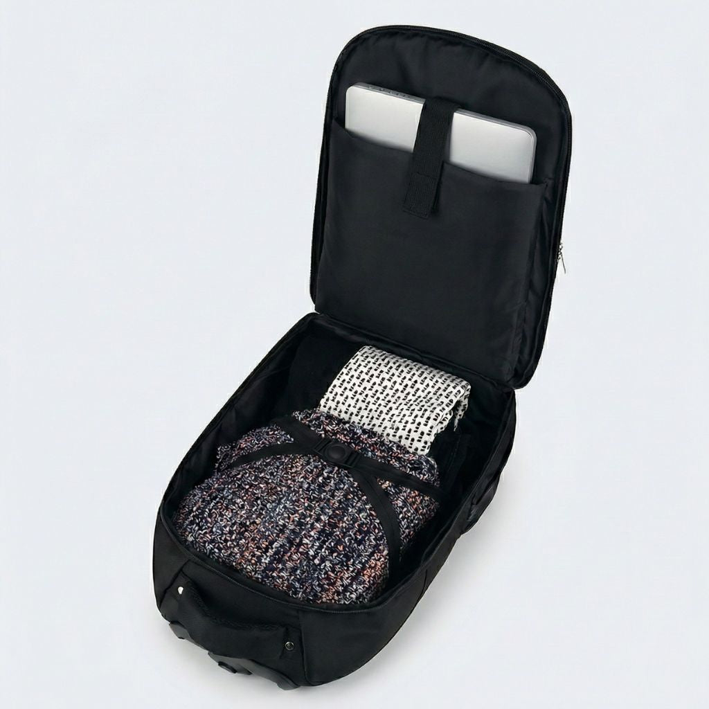 Vue plongeante dans le compartiment principal d'un sac à dos à roulettes noir avec ordinateur portable et vêtements Image