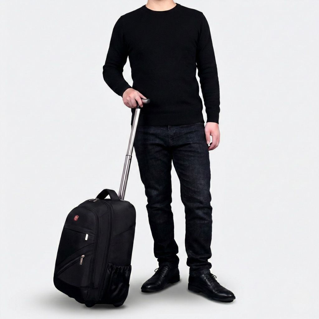 Homme en tenue sombre tirant un sac à dos à roulettes noir avec poignée télescopique déployée sur fond blanc Image