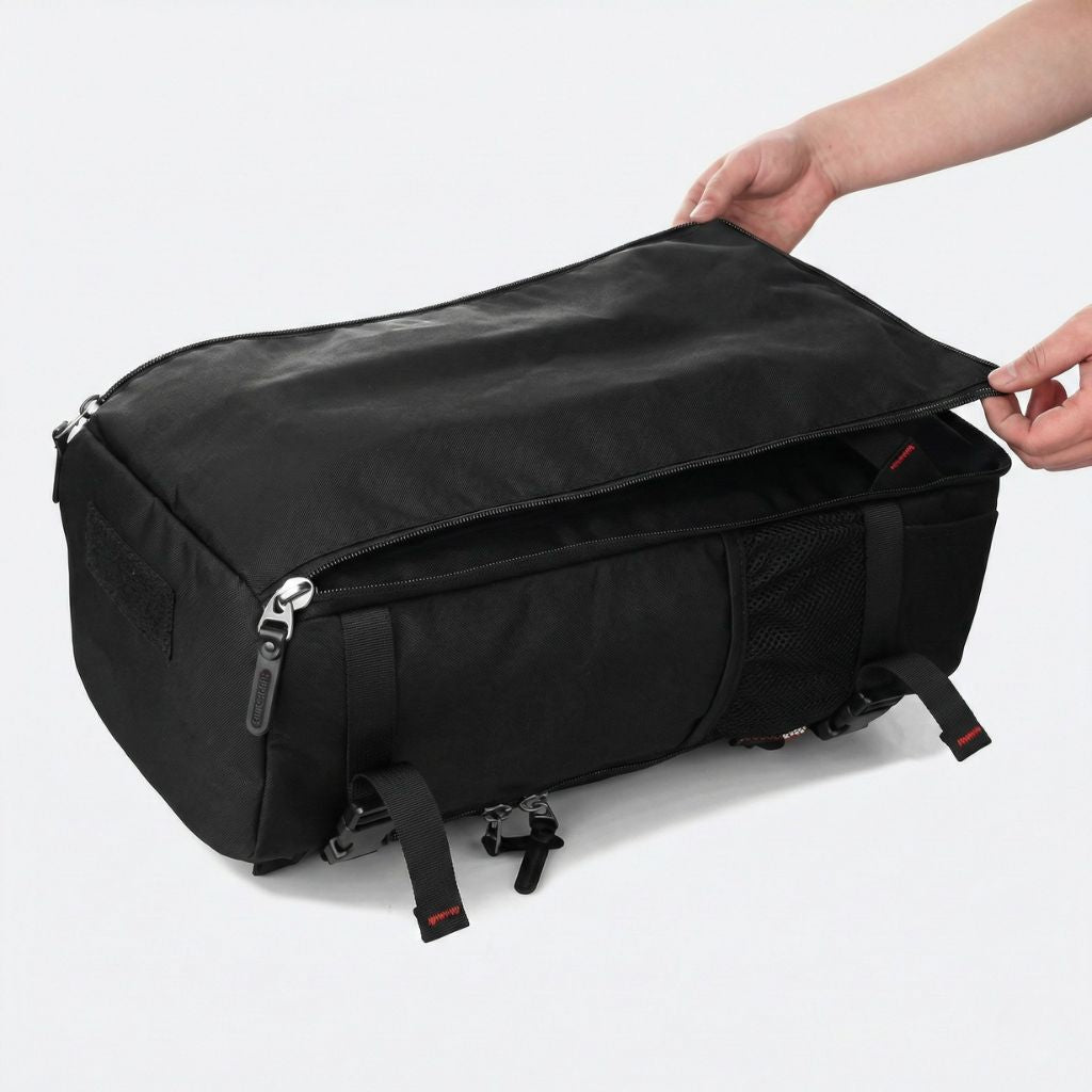 Grand sac de voyage noir transformé en duffle bag, main ouvrant le zip principal en vue horizontale