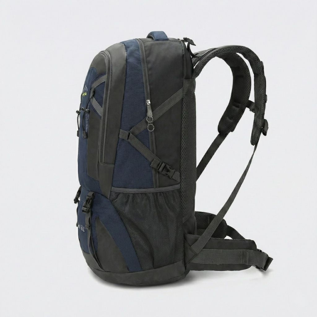 Sac à dos de voyage bleu marine 60L vu de profil, poche latérale filet, bretelles ergonomiques et sangles réglables