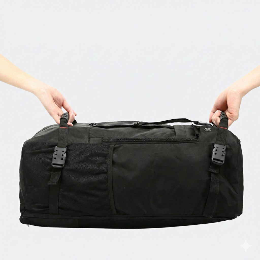 Deux mains tenant le sac de voyage noir en mode duffel horizontal par les poignées de transport rembourrées