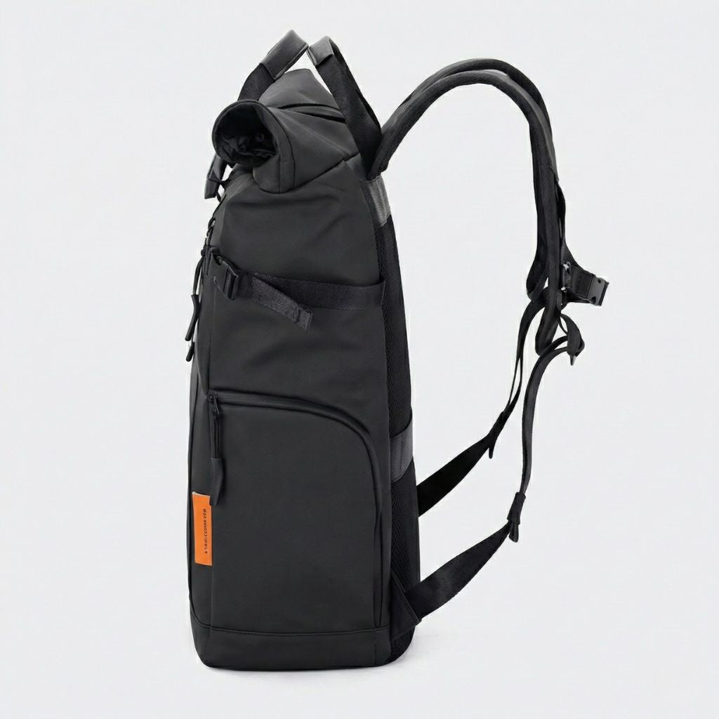 Sac à dos voyage roll-top noir étanche vu de profil, poche latérale zippée, bretelles réglables et languette orange