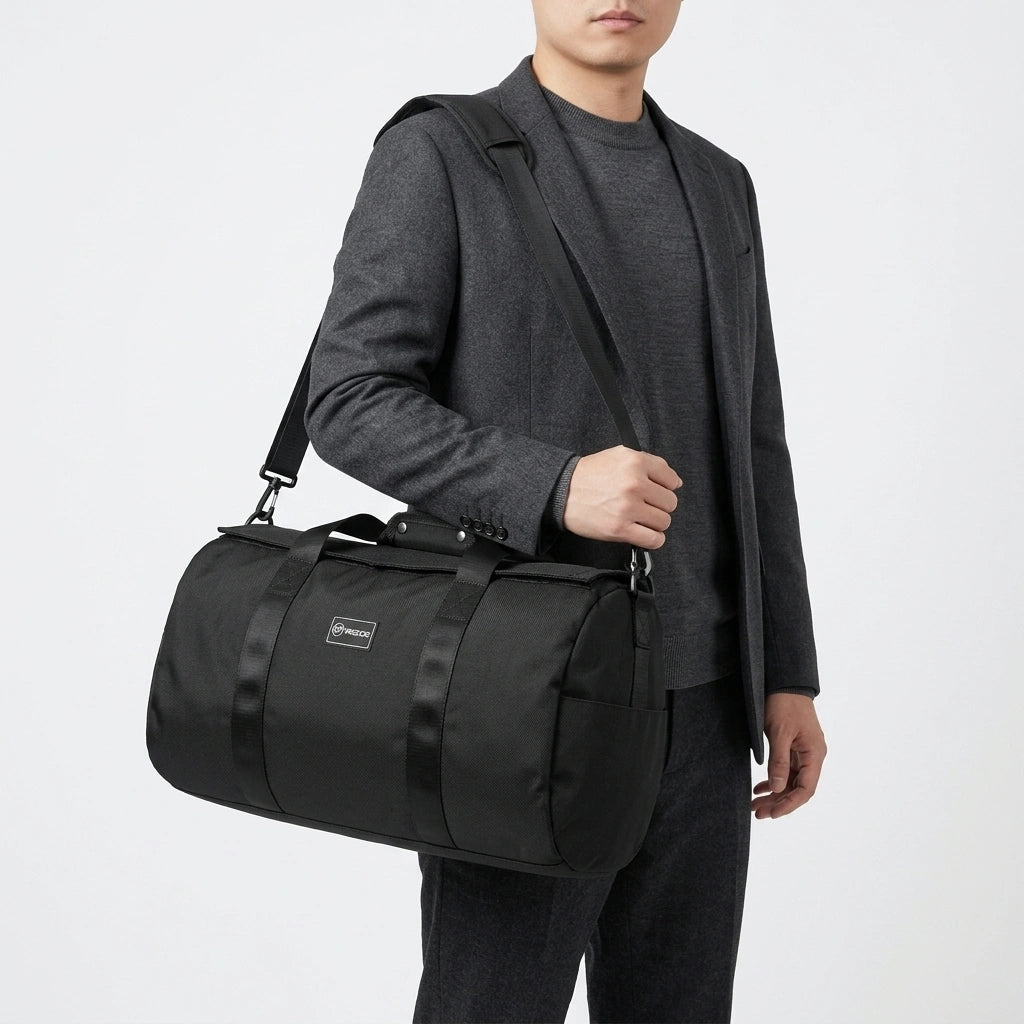 Homme en veste grise portant un sac de sport duffel noir 34L en bandoulière sur l'épaule gauche Image