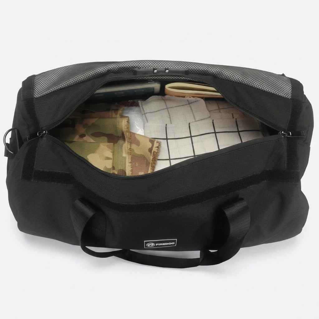 Intérieur du sac de sport noir 34L chargé de vêtements, poche filet sur couvercle et cadenas intégré