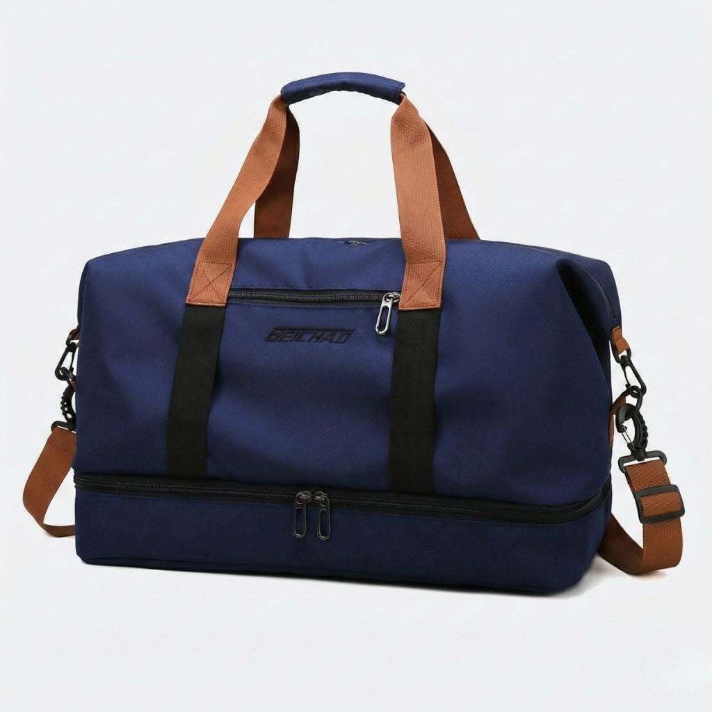 Sac de sport bleu marine avec poignées et bandoulière caramel, poche chaussures séparée zippée en bas, vue 3/4