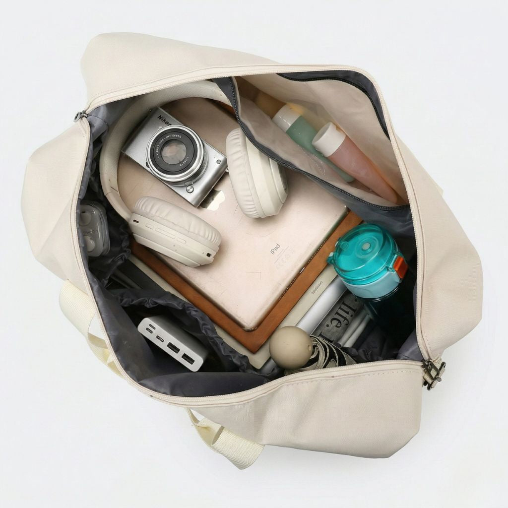 Sac de voyage de sport beige ouvert vu du dessus, rempli d'affaires, casque audio, appareil photo et accessoires