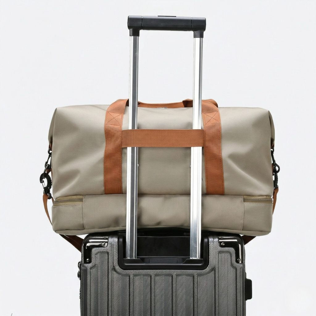 Sac de sport kaki posé sur une valise cabine grâce à sa sangle de maintien sur la poignée trolley, vue de dos