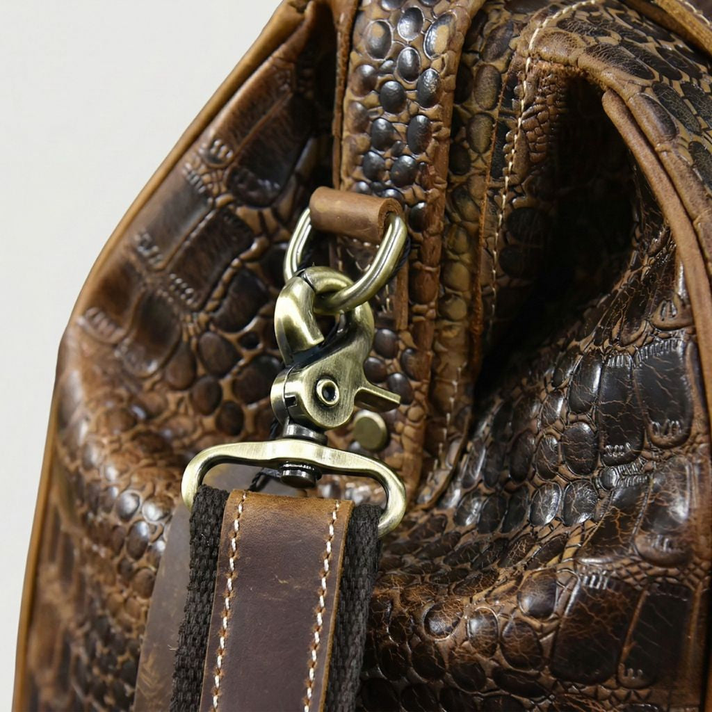 Mousqueton en laiton bronze vieilli du sac de voyage cuir croco, accroché à l'anneau en cuir, finition antique