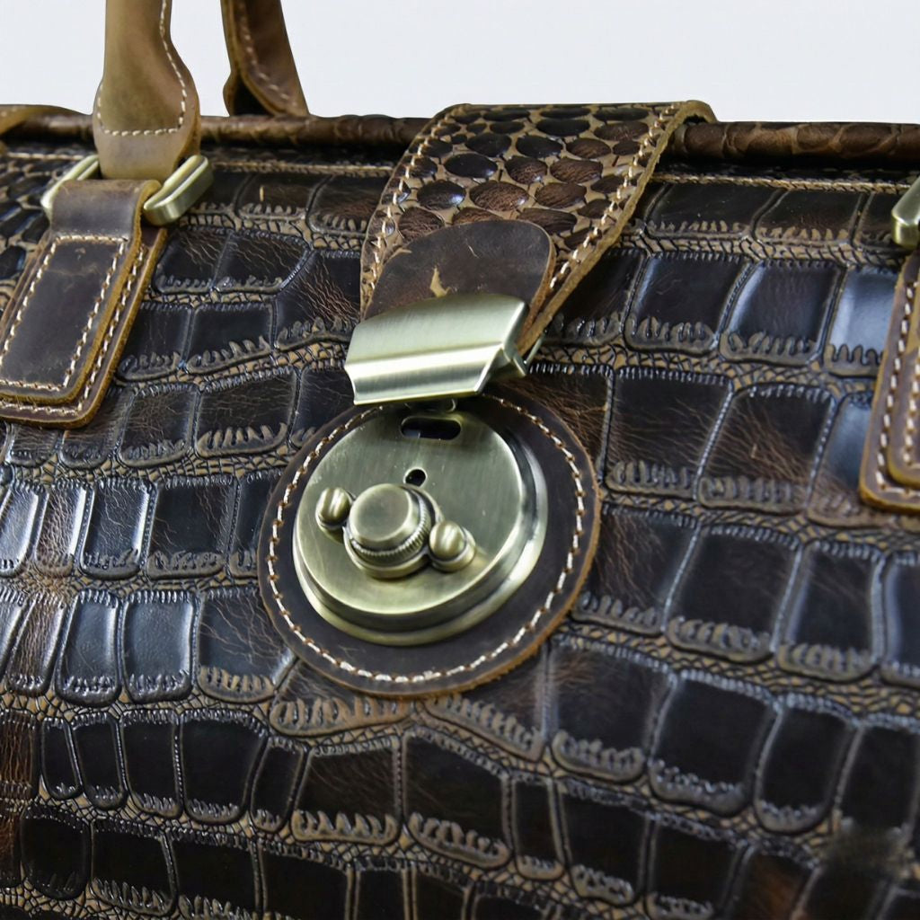 Gros plan du fermoir rotatif circulaire en laiton vieilli du sac de voyage cabine cuir croco