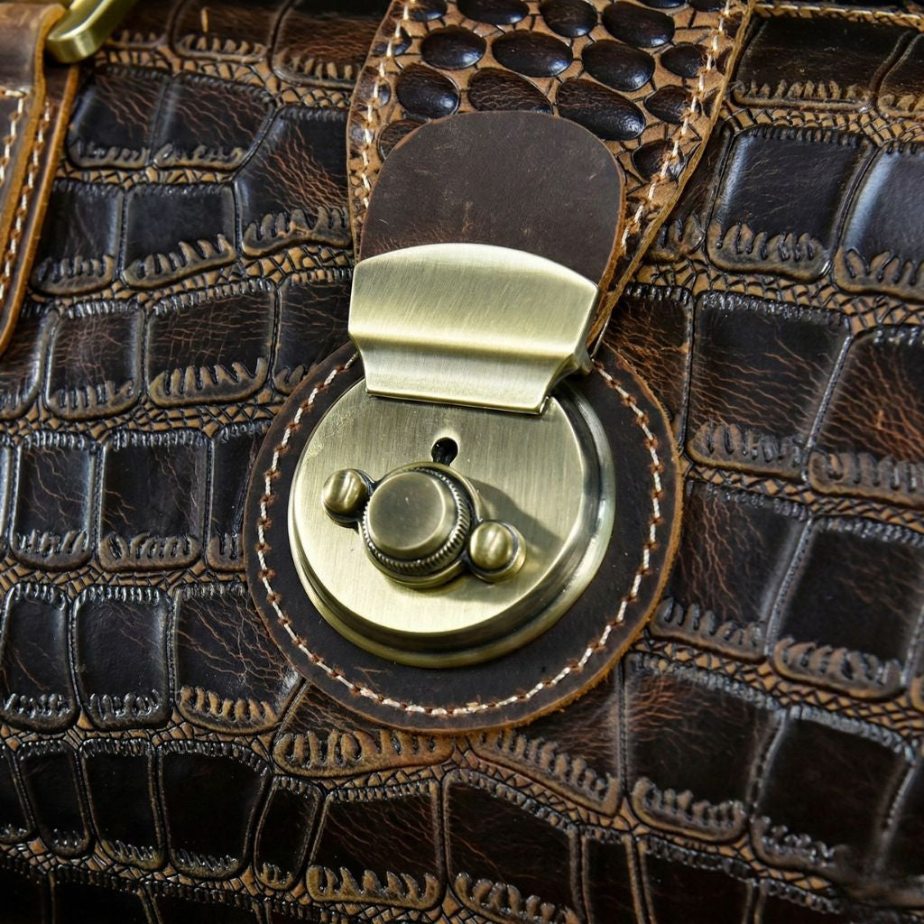Gros plan fermoir rotatif en bronze ouvert du sac de voyage cabine cuir croco, mécanisme de verrouillage