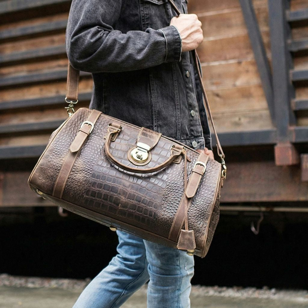 Homme portant le sac de voyage cabine cuir croco en bandoulière en extérieur, style voyageur urbain