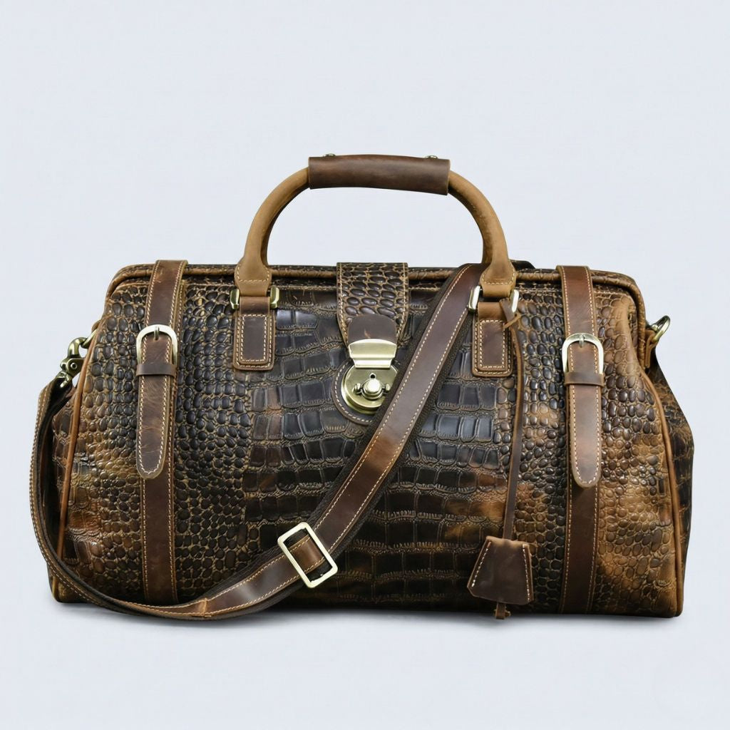 Sac de voyage cabine cuir croco brun, vue de face avec bandoulière en diagonale, ferrures laiton vieilli