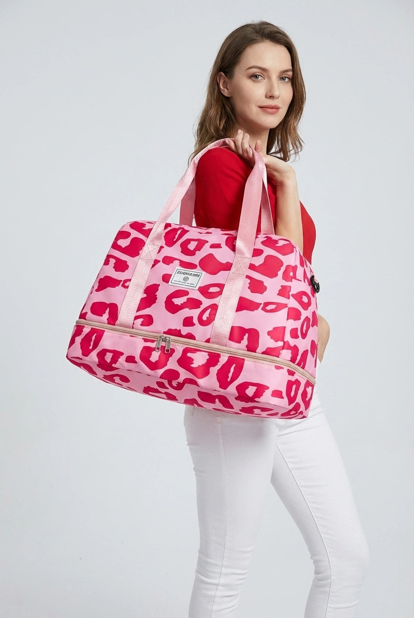Sac de voyage femme rose léopard fuchsia tenu par les poignées, compartiment chaussures et bandoulière amovible