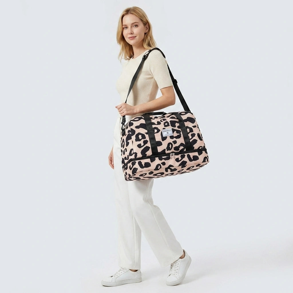 Sac de voyage femme beige à motifs léopard noir porté en bandoulière sur l'épaule, compartiment chaussures zippé