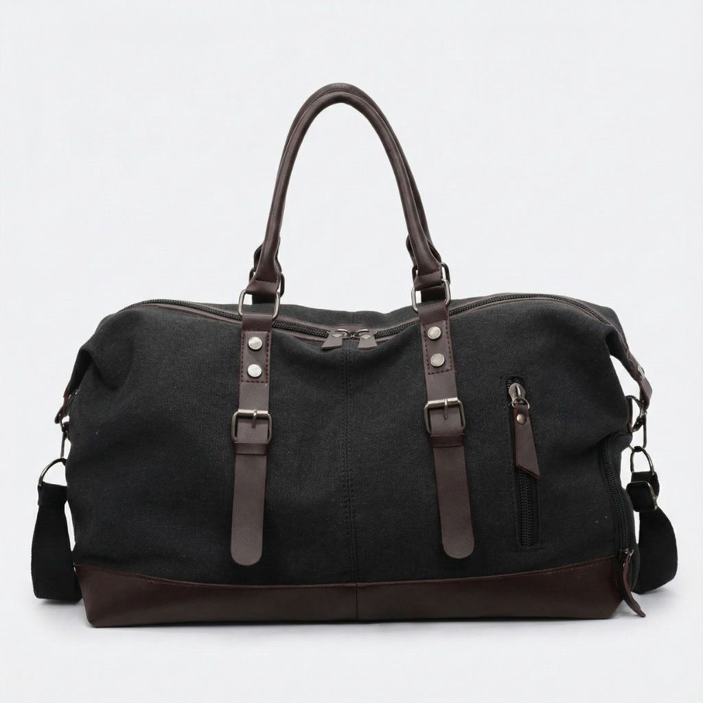 Sac de voyage en toile noire avec poignées en cuir marron, bandoulière réglable et poche latérale zippée