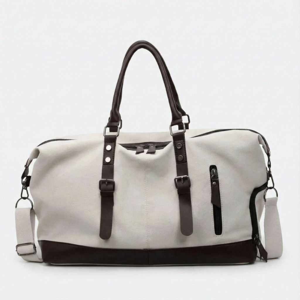 Sac de voyage en toile blanc avec poignées en cuir marron, bandoulière réglable et poche latérale zippée