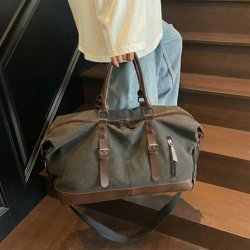 Sac de voyage en toile kaki avec poignées en cuir marron et poche latérale zippée, porté à la main Image