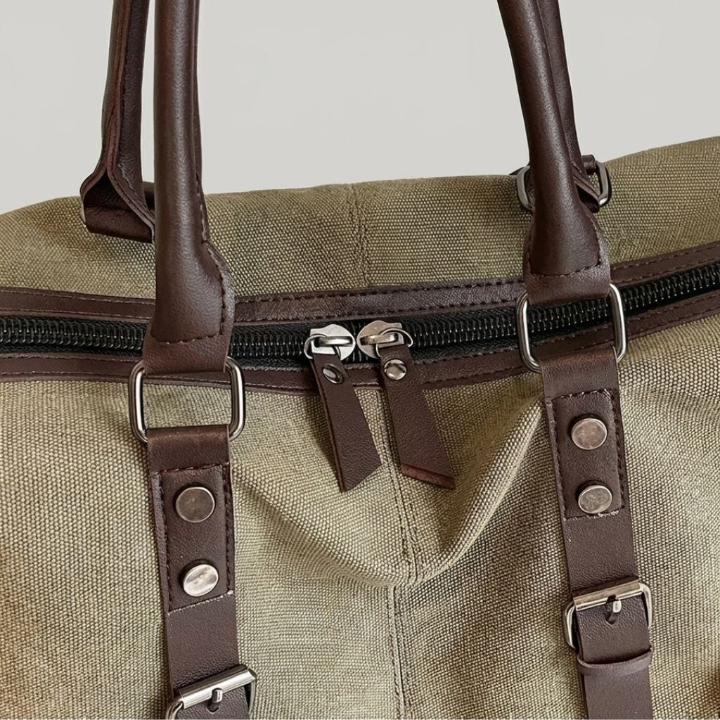 Sac de voyage en toile kaki avec fermetures éclair métalliques et poignées en cuir marron en gros plan