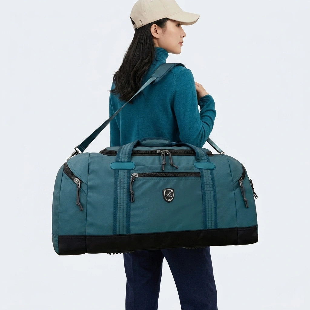 Femme en pull turquoise portant un grand sac de voyage bleu canard en bandoulière, vue de dos