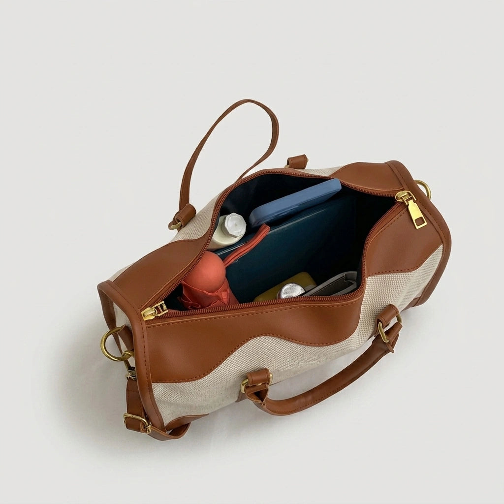 Sac de voyage en toile beige camel ouvert de dessus, révélant un intérieur spacieux avec effets personnels