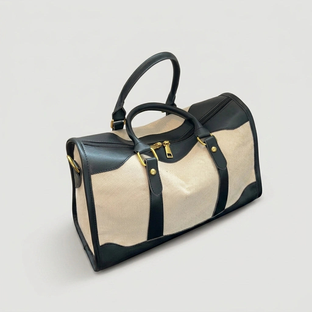 Sac de voyage style vintage en toile beige et cuir noir, vue 3/4 avec hardware doré et bandoulière noire