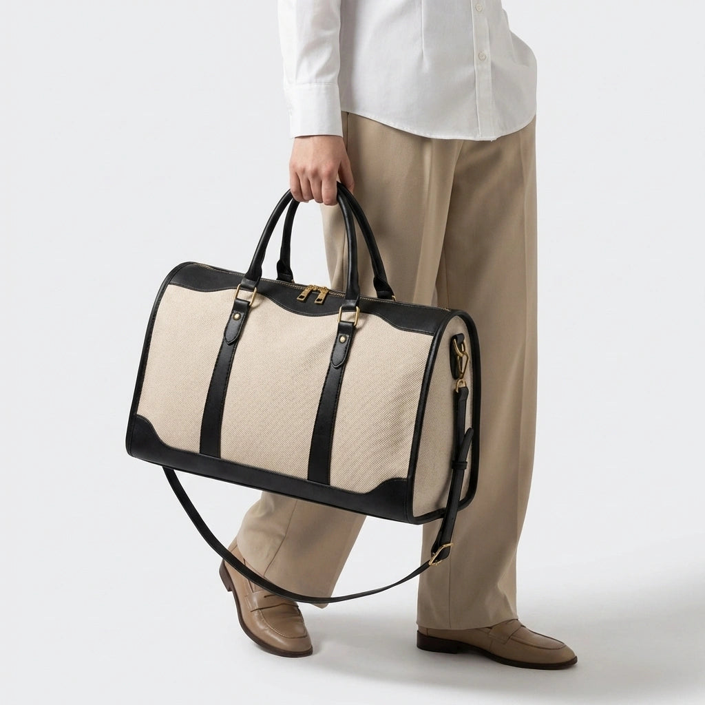 Sac de voyage vintage noir grande taille tenu à la main, mannequin en chemise blanche et pantalon beige