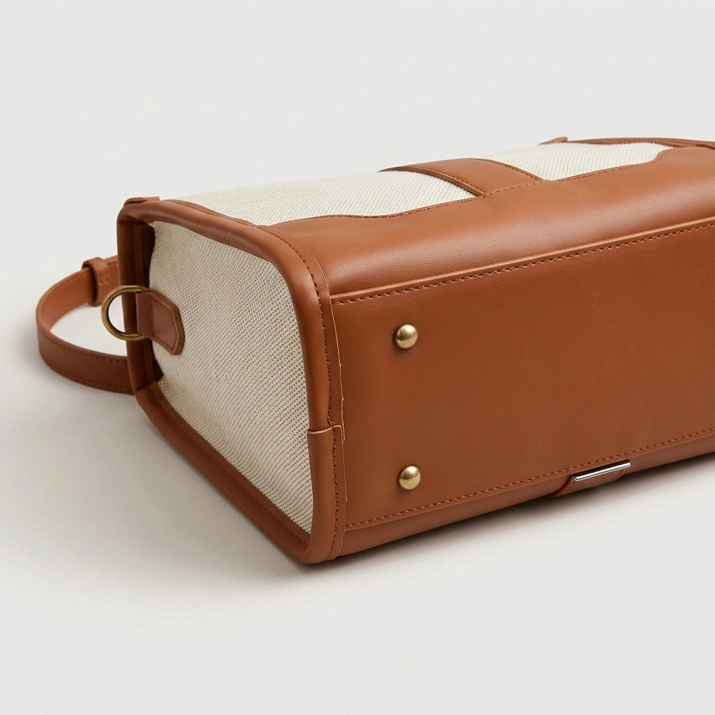 Gros plan sur le dessous du sac de voyage vintage camel, rivets dorés sur cuir cognac et base structurée