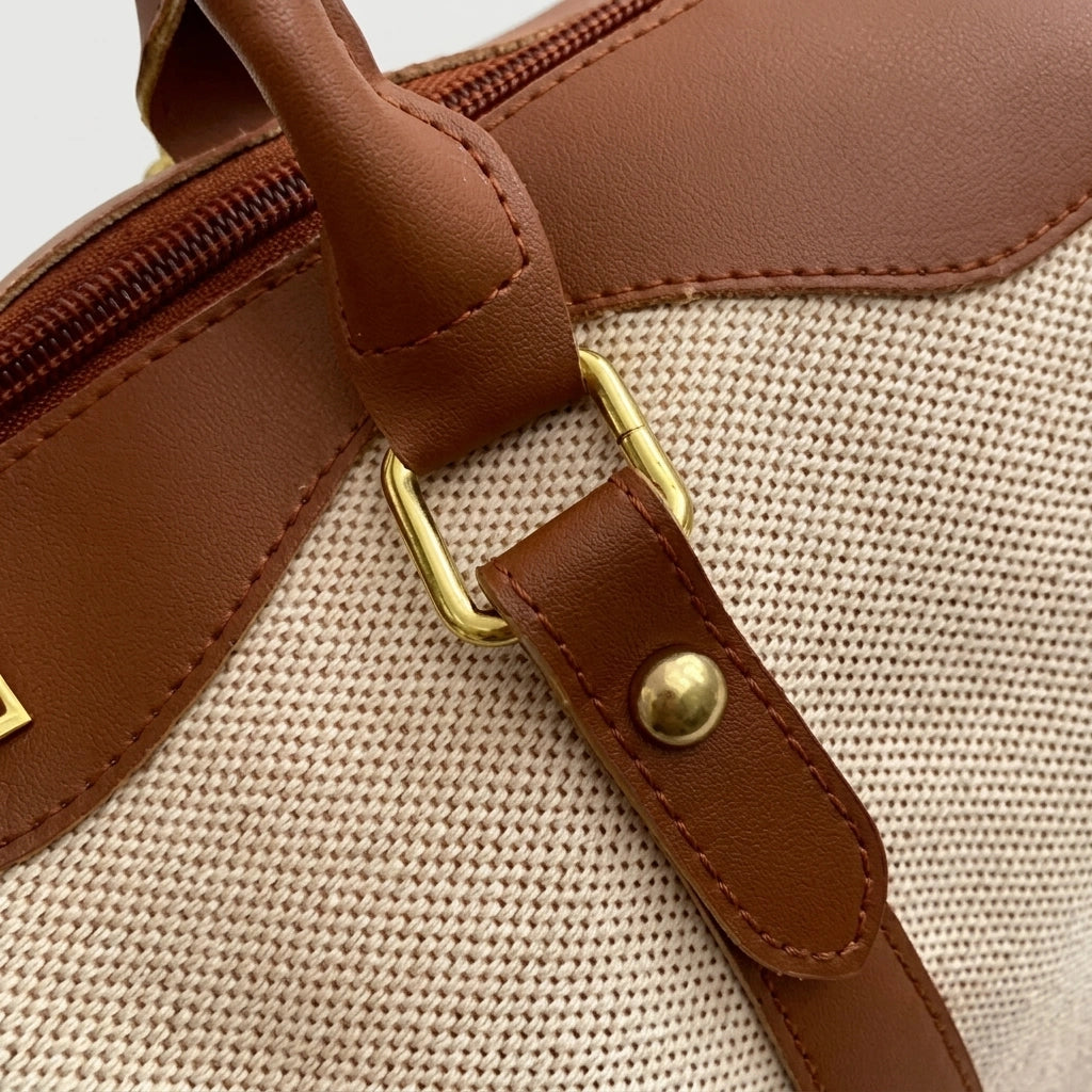 Détail de l'attache bandoulière d'un sac de voyage vintage, cuir cognac cousu sur toile beige naturelle