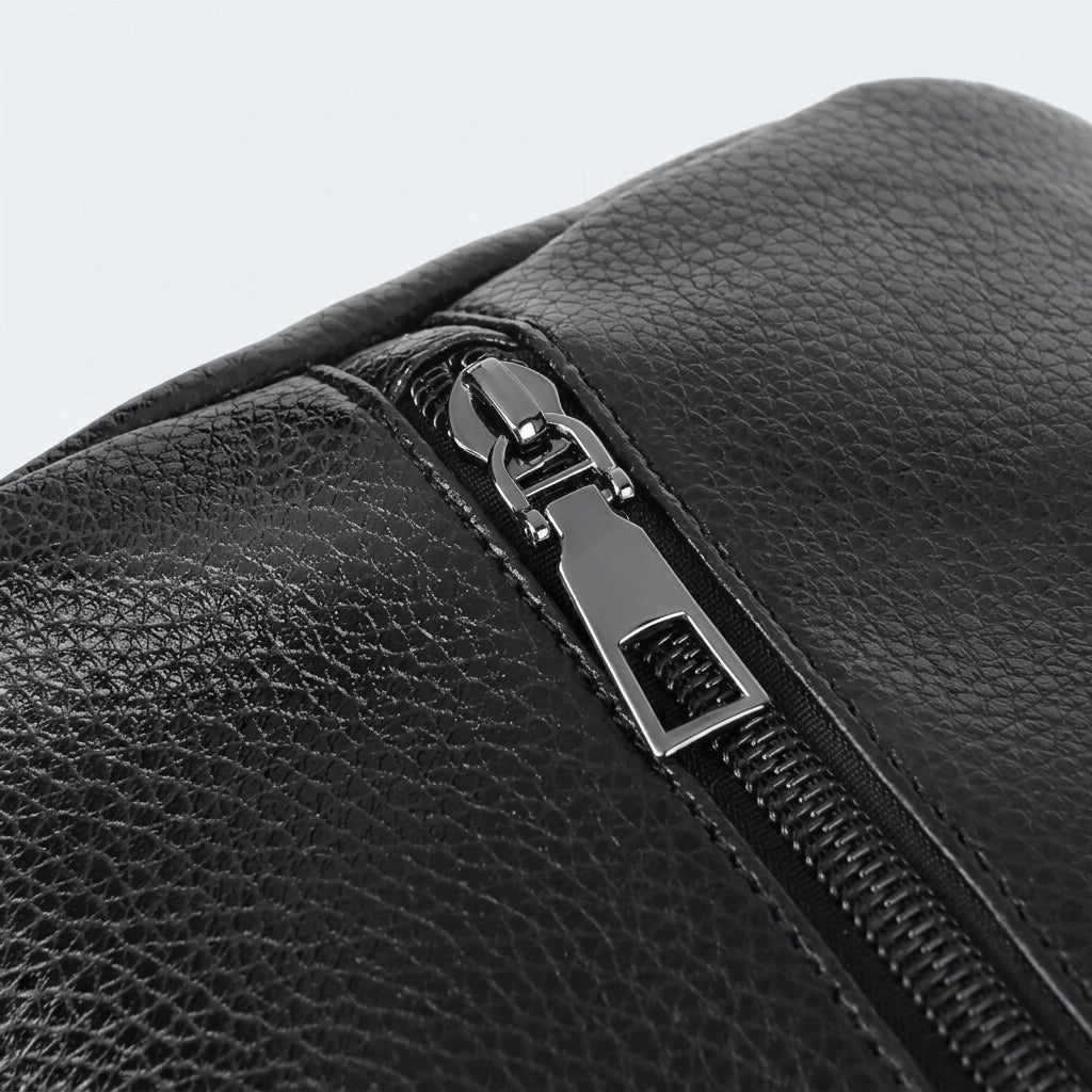Gros plan sur la fermeture éclair en métal gunmetal du sac de voyage homme en simili cuir grainé noir