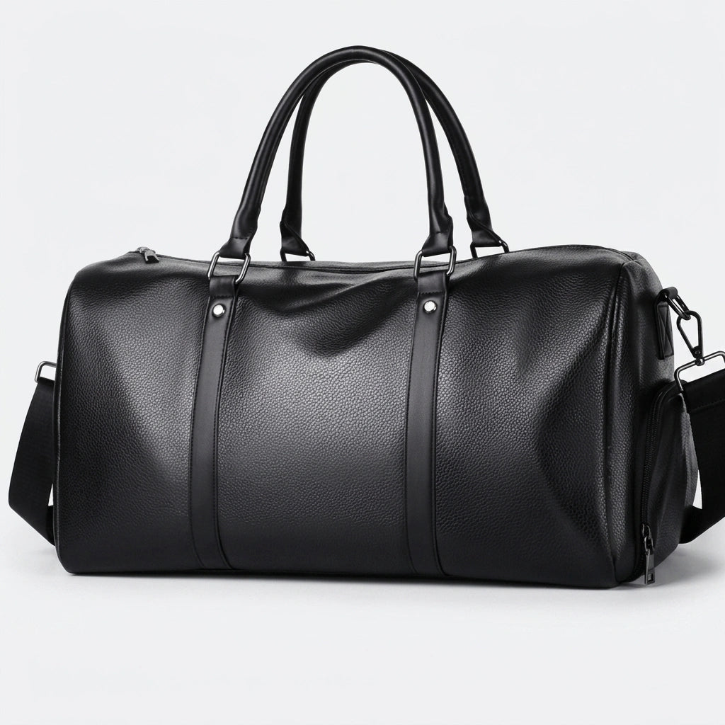 Sac de voyage homme en simili cuir noir, vue 3/4, poignées rondes, bandoulière et fermeture zippée