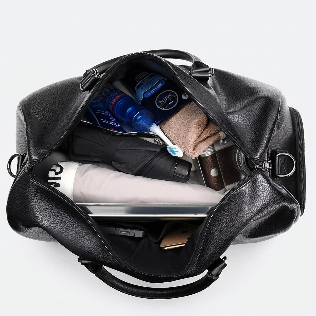 Sac de voyage en simili cuir noir ouvert vu du dessus, contenu organisé : ordinateur, produits de toilette Image