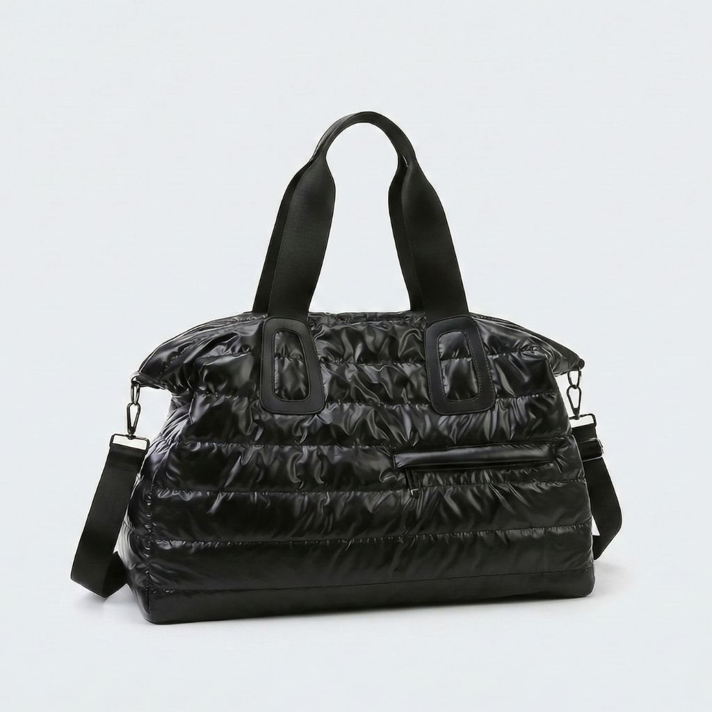 Sac de voyage matelassé noir grand format souple avec poignées et bandoulière amovible sur fond uni