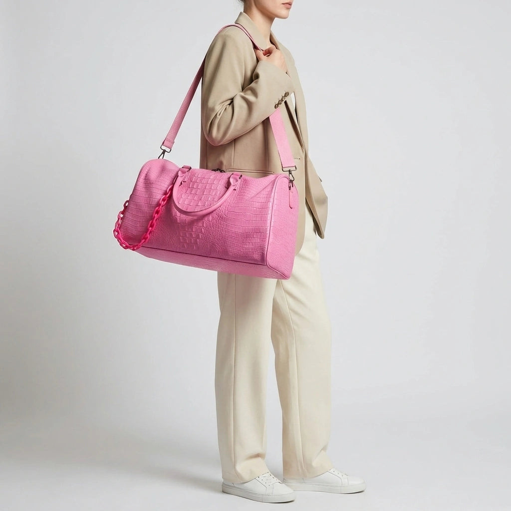 Sac de voyage rose croco grande capacité porté par une femme en blazer beige, vue de face complète