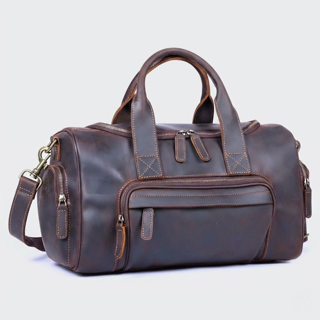 Sac de voyage en cuir véritable marron foncé, vue 3/4, poignées rondes, poche frontale zippée et bandoulière