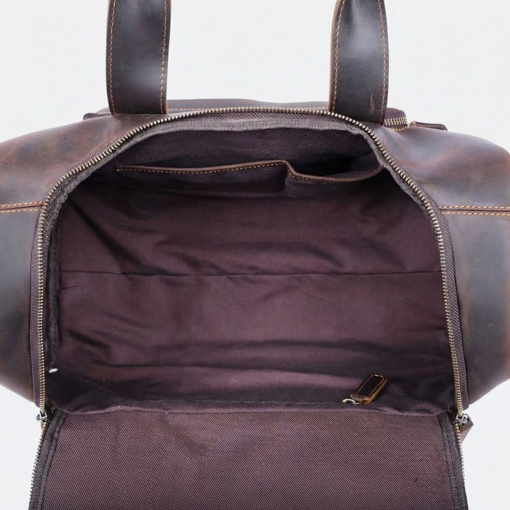 Intérieur du sac de voyage en cuir marron foncé ouvert, doublure bordeaux, poches intérieures et grande capacité