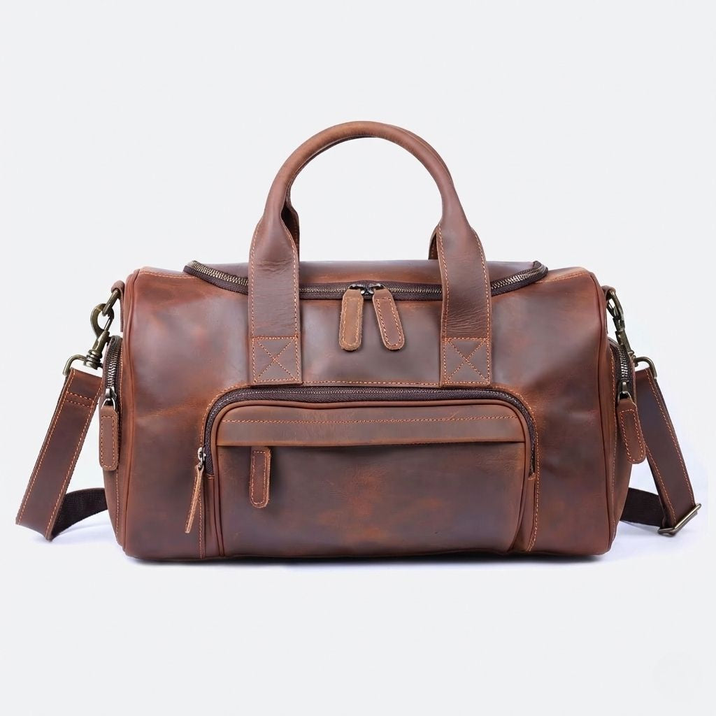 Sac de voyage en cuir marron cognac vu de face, double poignée arrondie, large poche frontale zippée et bandoulière
