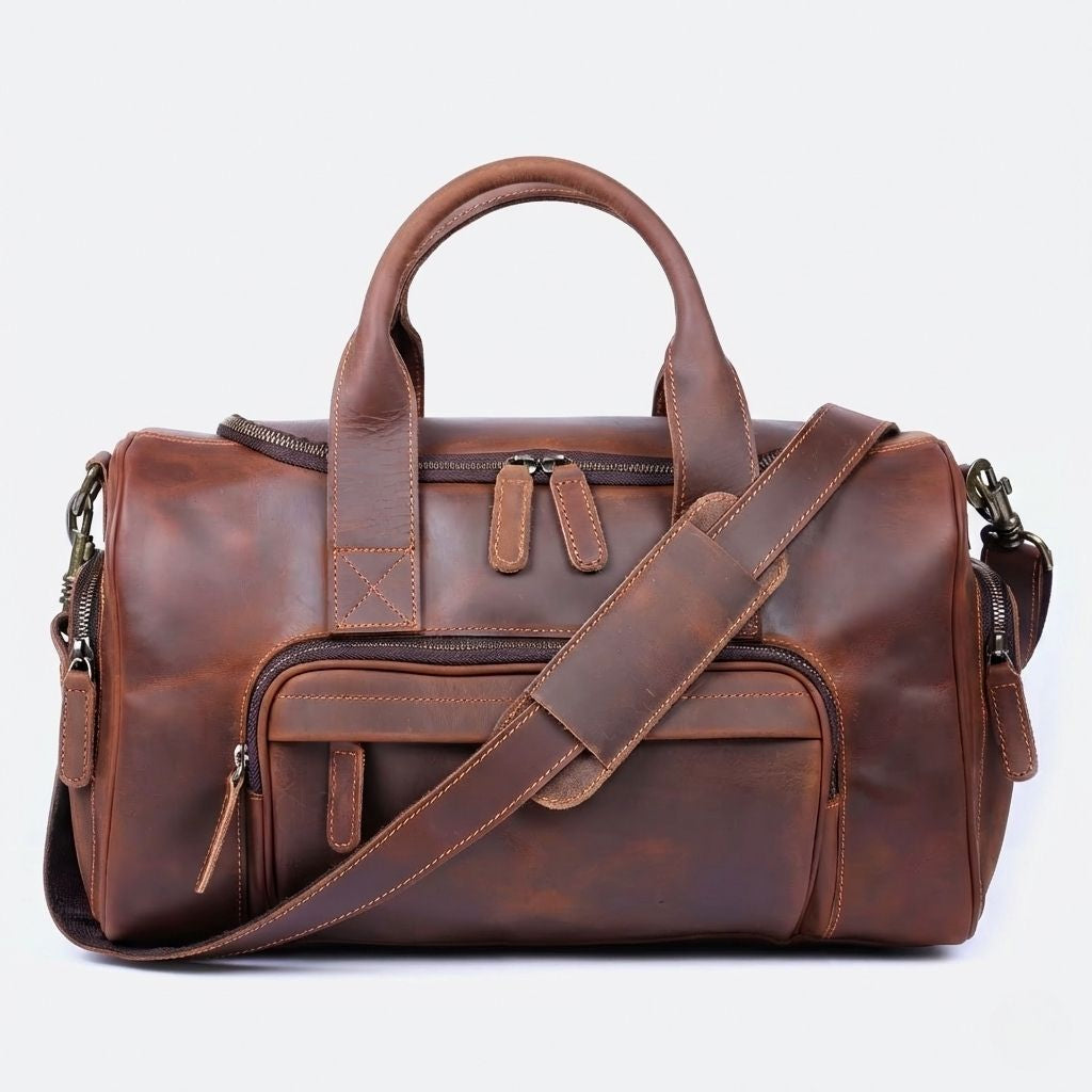 Sac de voyage en cuir marron cognac vu de face avec bandoulière, poche frontale zippée et coutures contrastées