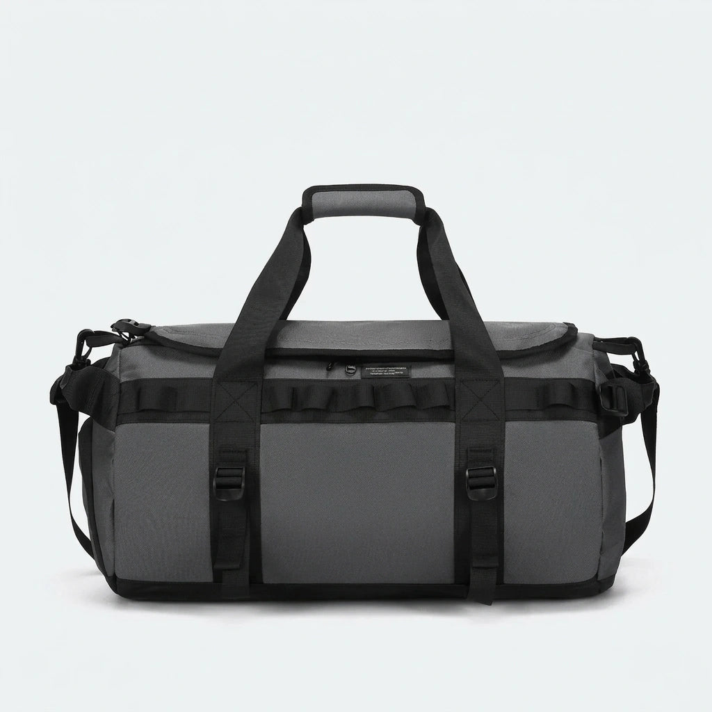 Sac de voyage duffle gris anthracite avec renforts noirs et étiquette frontale vu de face en studio