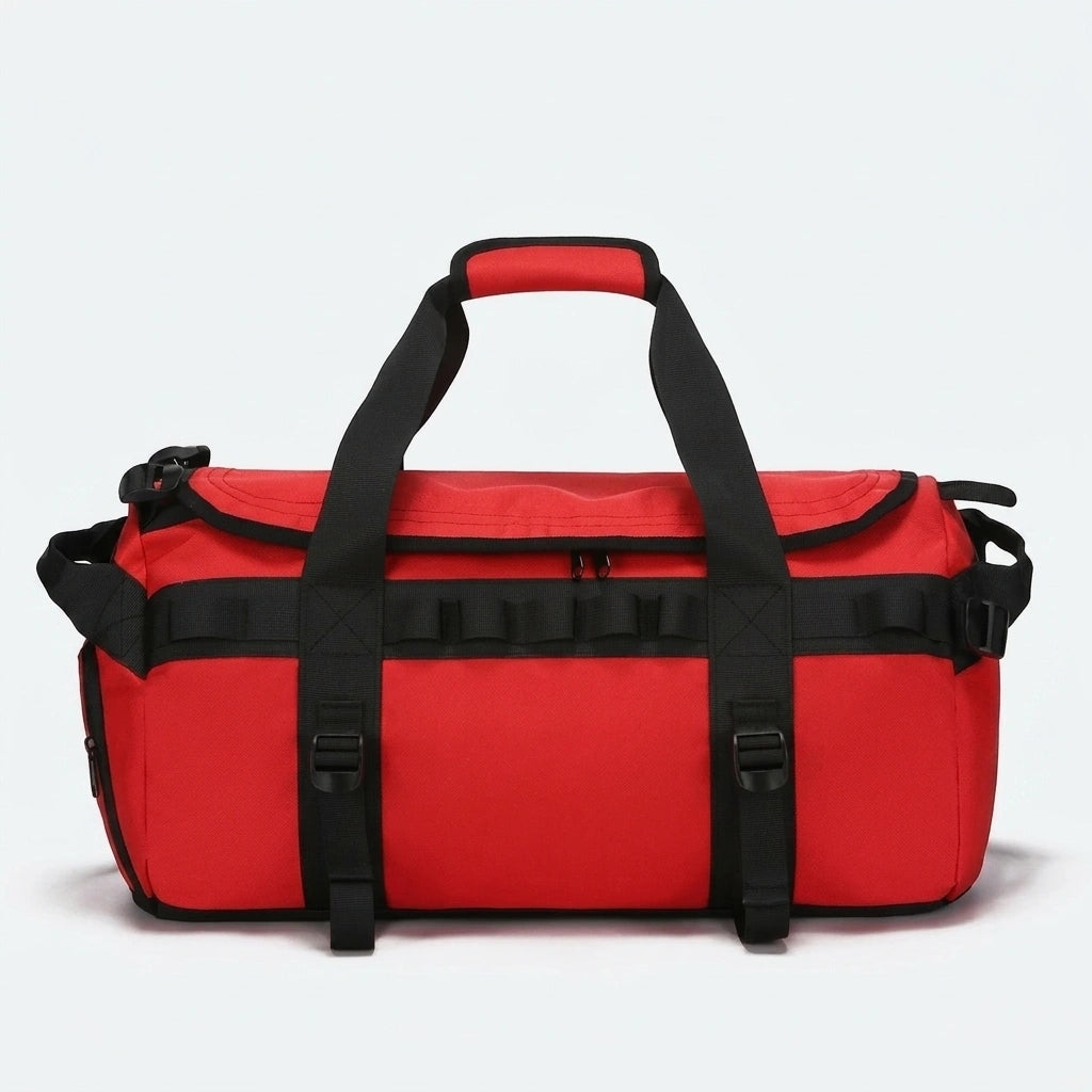 Sac de voyage duffle rouge vif avec sangles de compression et attaches noires vu de face sur fond studio