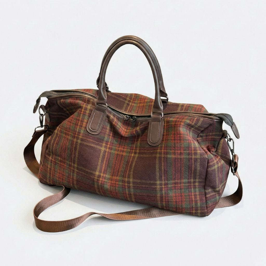 Sac de voyage en toile tartan bordeaux et vert, vue 3/4, poignées en cuir brun, bandoulière et fermeture zippée