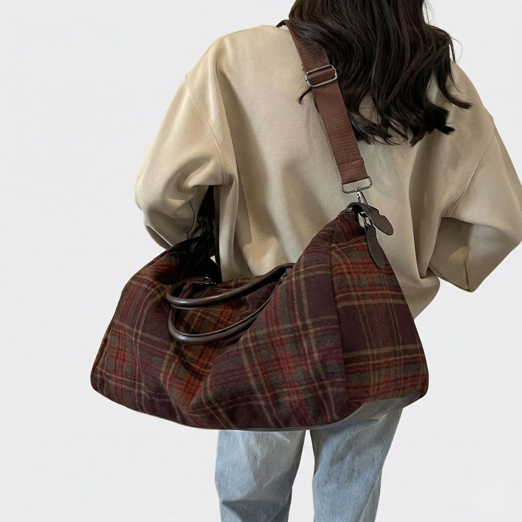Femme portant en bandoulière un sac de voyage en toile tartan bordeaux, vue de dos, style rétro anglais décontracté