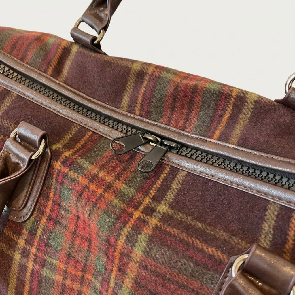 Détail de la fermeture double curseur bronze du sac de voyage en toile tartan bordeaux à motif écossais