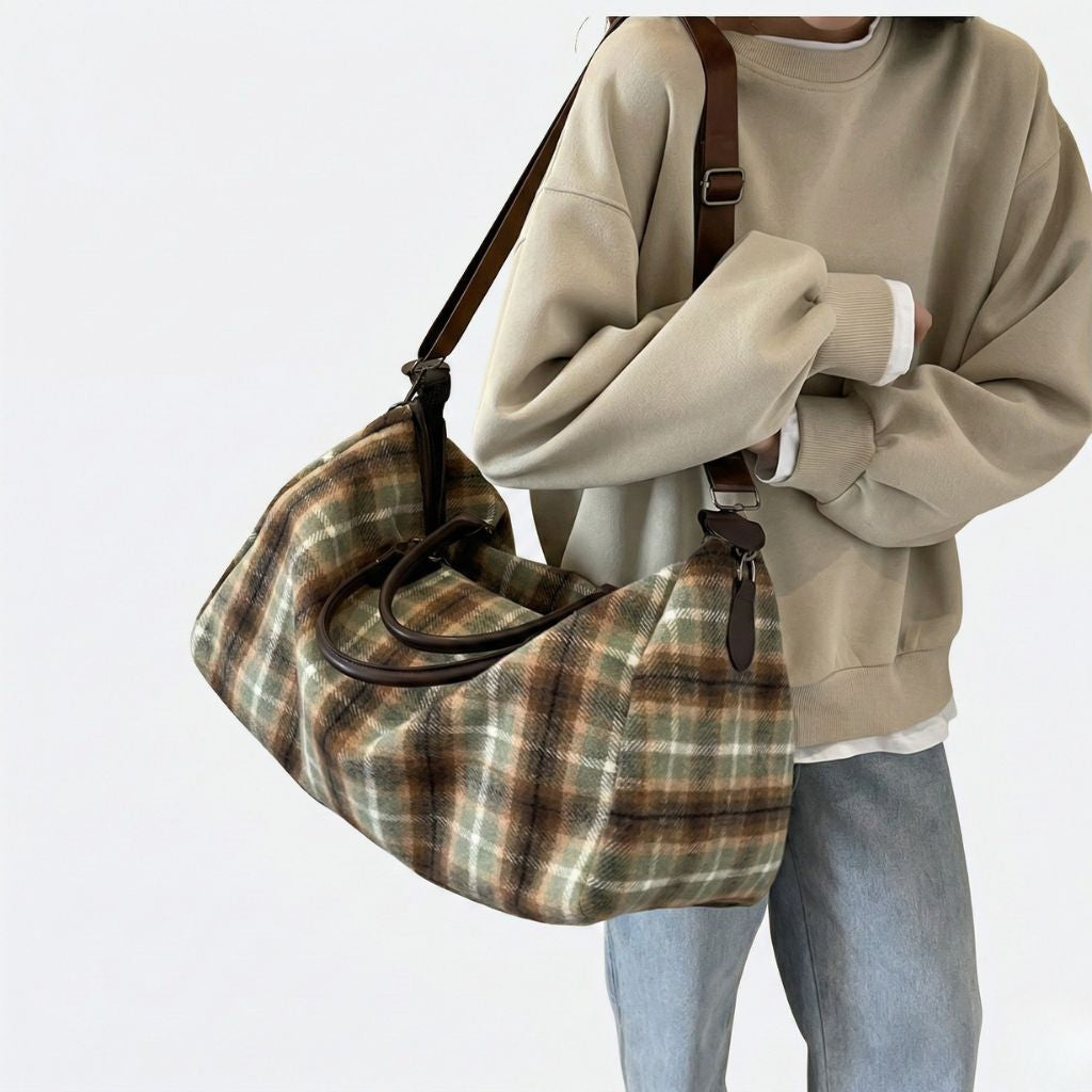 Personne portant en bandoulière un sac de voyage en toile tartan kaki, vue de face, look casual vintage rétro