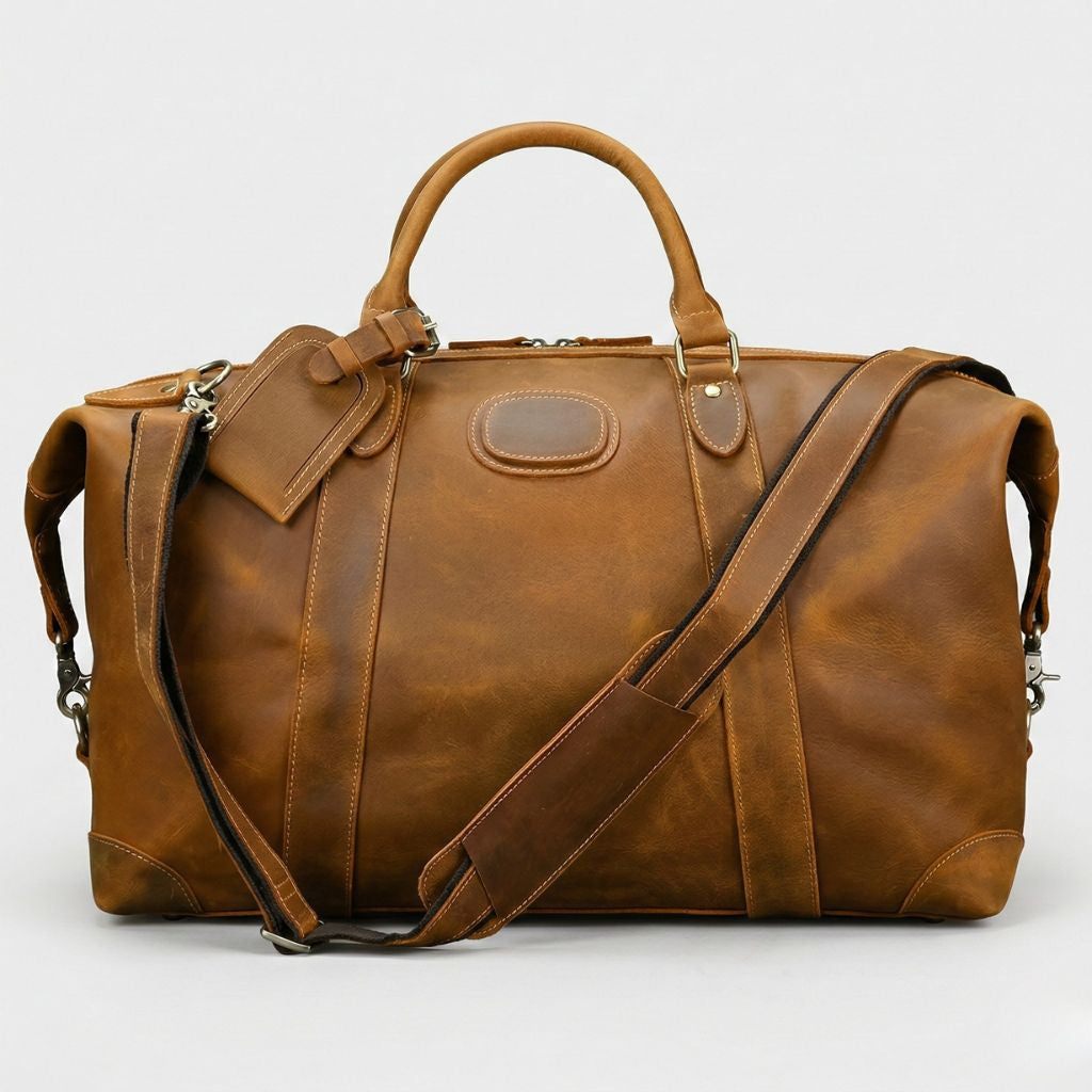 Sac de voyage en cuir vachette cognac, deux poignées rondes, étiquette bagage et bandoulière réglable