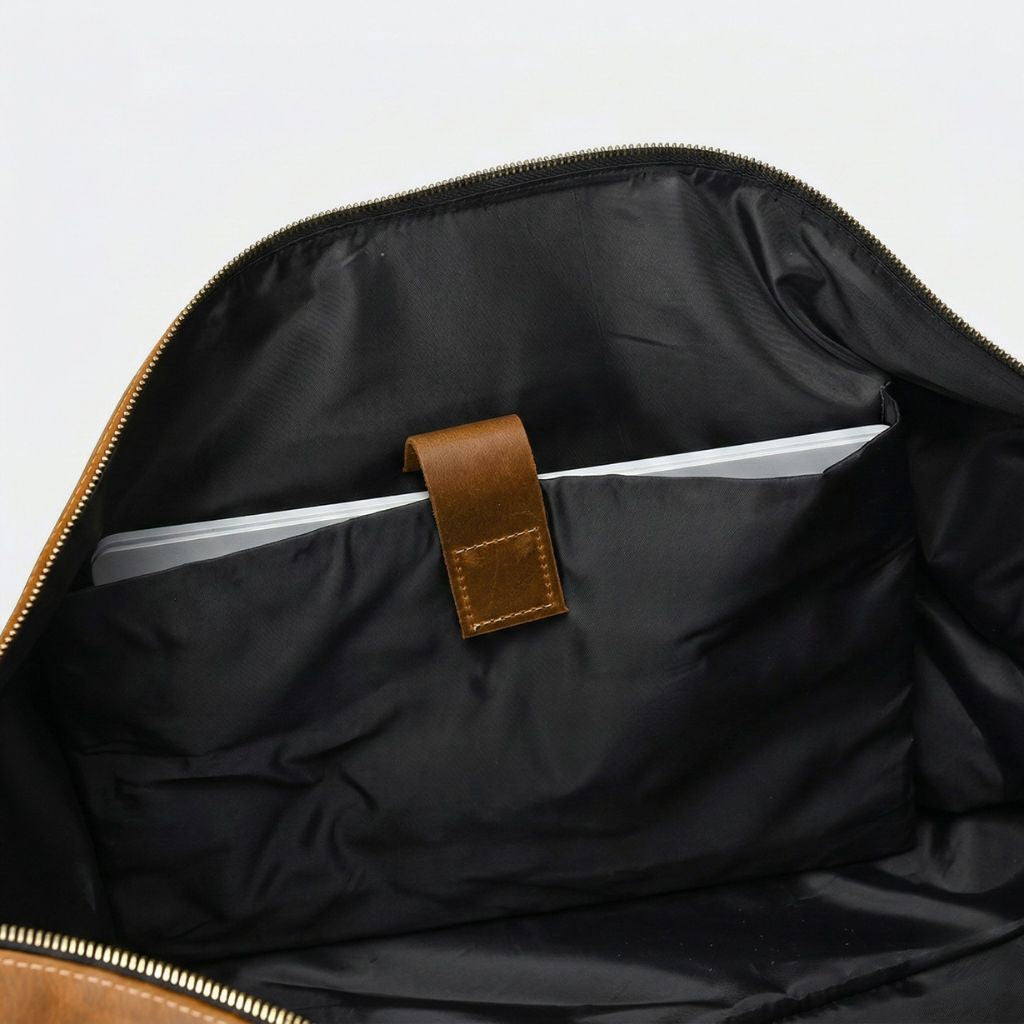 Poche pour ordinateur intérieure en nylon noir, languette cuir cognac et tranche du laptop argenté visible
