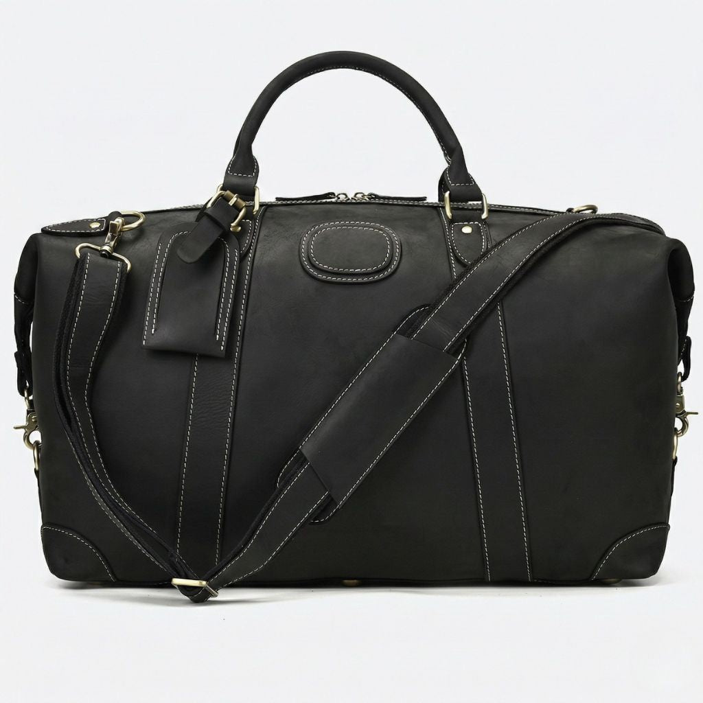 Sac de voyage en cuir noir mat, surpiqûres blanches contrastées, étiquette voyage et bandoulière réglable