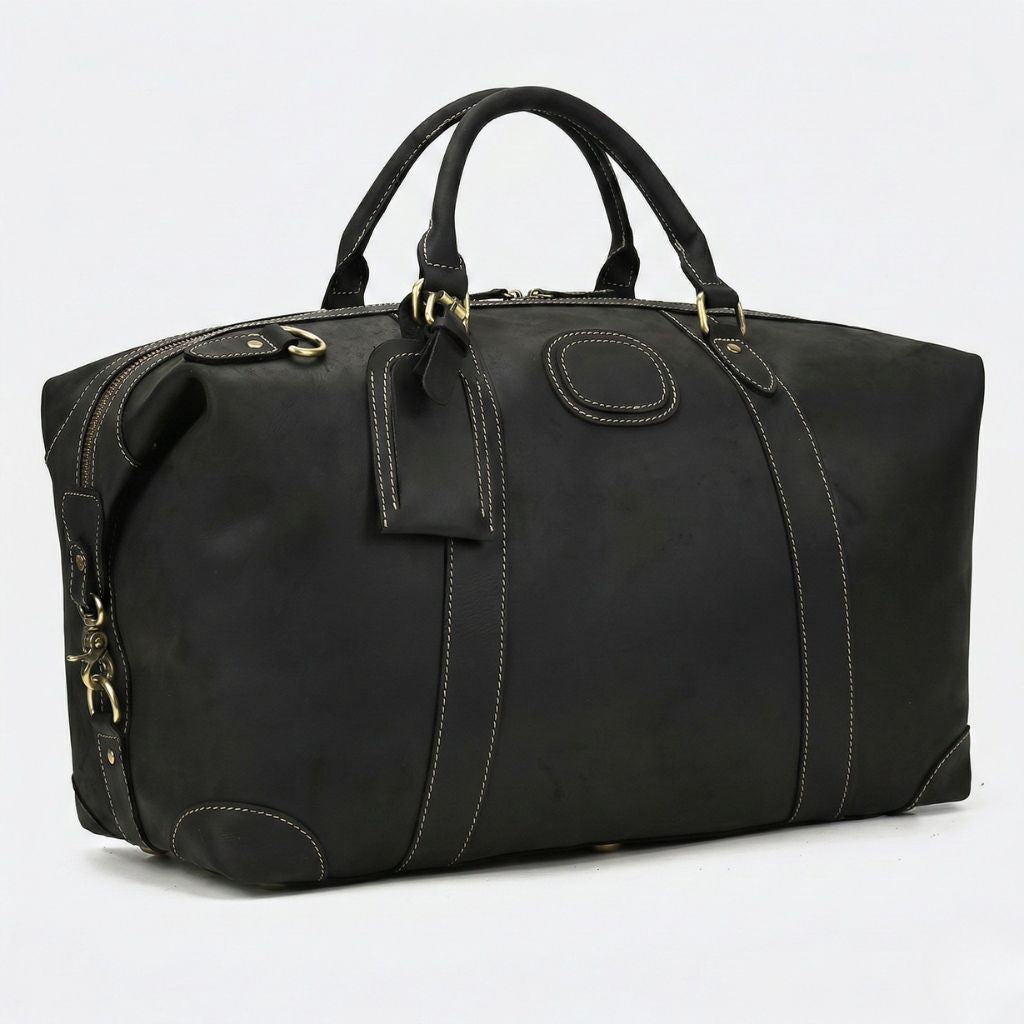 Vue trois-quarts du sac de voyage en cuir noir mat, profondeur et fermeture zippée latérale visibles